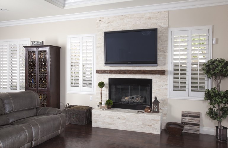 White plantation shutters in a New York City living room with plank hardwood floors.